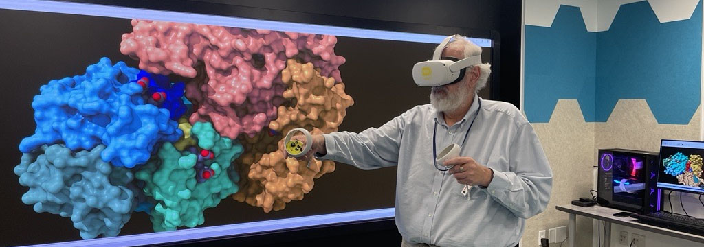 staff member in VR headset with molecule on large screen behind him